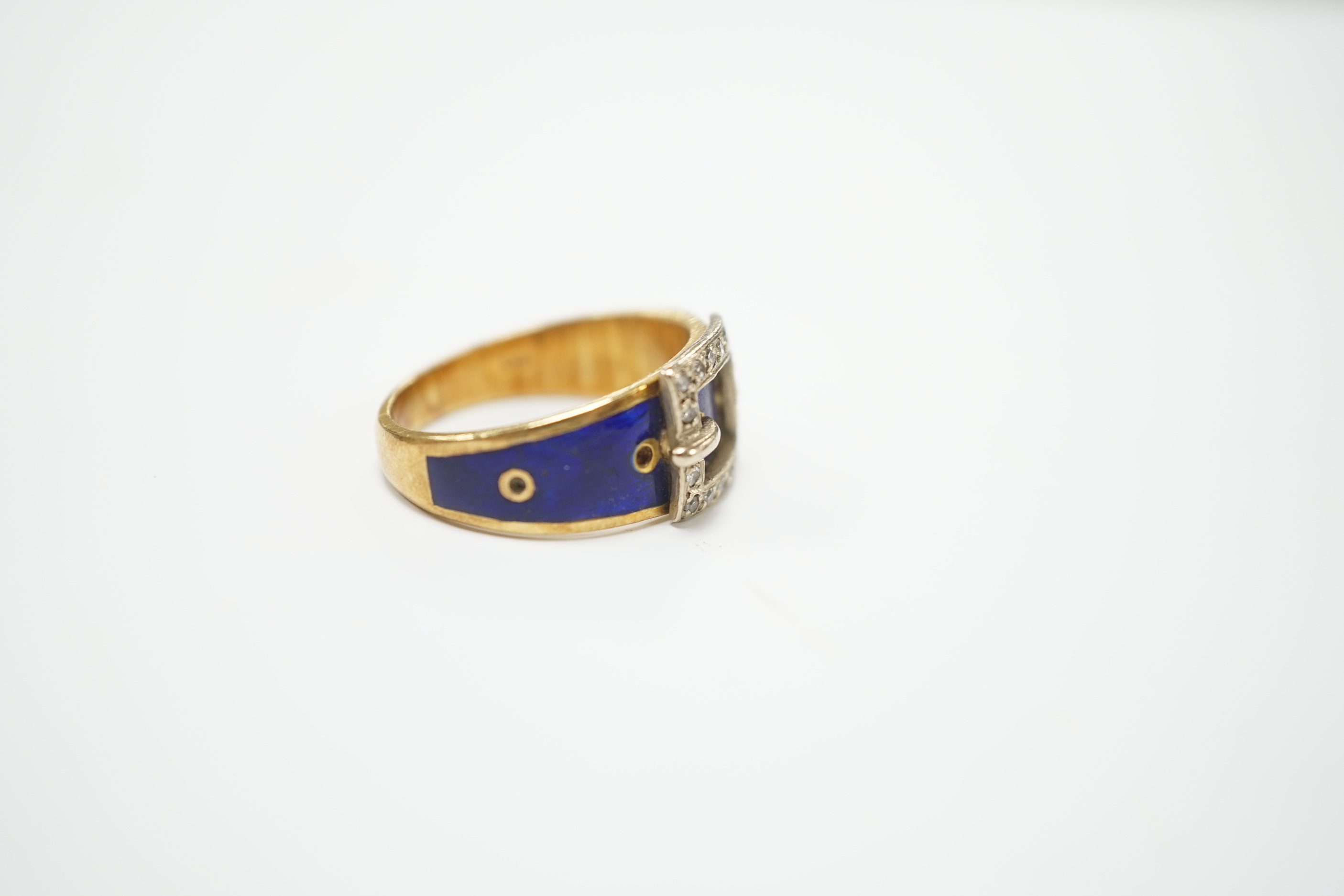 An early 20th century 18ct, diamond chip and blue enamel set buckle ring, size Q, gross weight 8.9 grams.